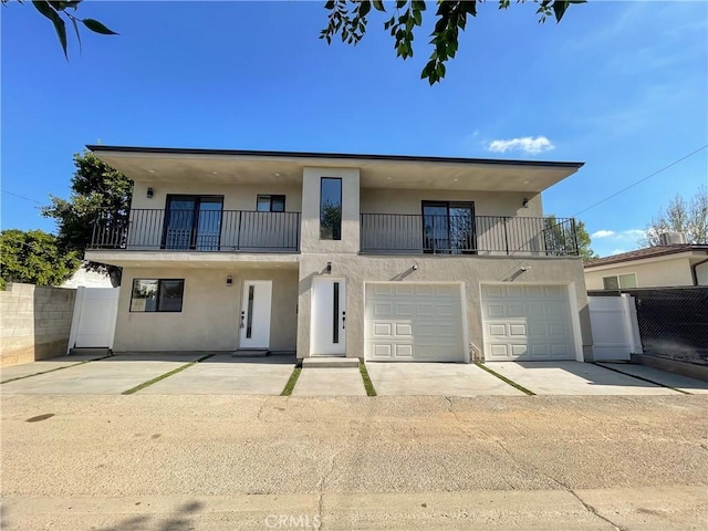 view of property with a garage, fence, a balcony, and stucco siding