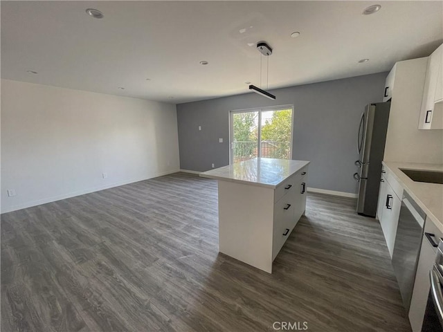 kitchen featuring stainless steel appliances, white cabinets, open floor plan, light countertops, and a center island