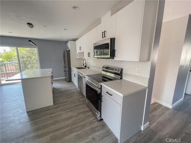 kitchen with dark wood-type flooring, a sink, baseboards, white cabinets, and appliances with stainless steel finishes