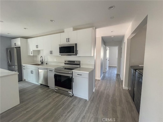 kitchen featuring washing machine and clothes dryer, stainless steel appliances, light countertops, white cabinets, and a sink