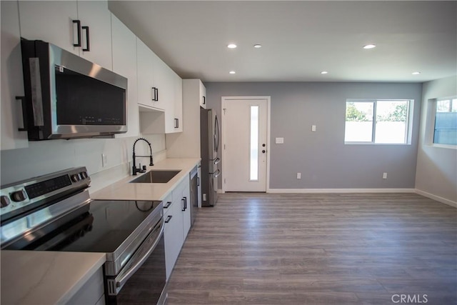 kitchen with white cabinets, appliances with stainless steel finishes, light countertops, and a sink