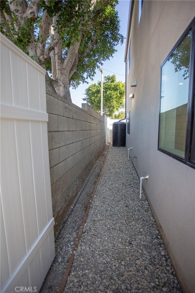 view of property exterior with central AC, fence, and stucco siding