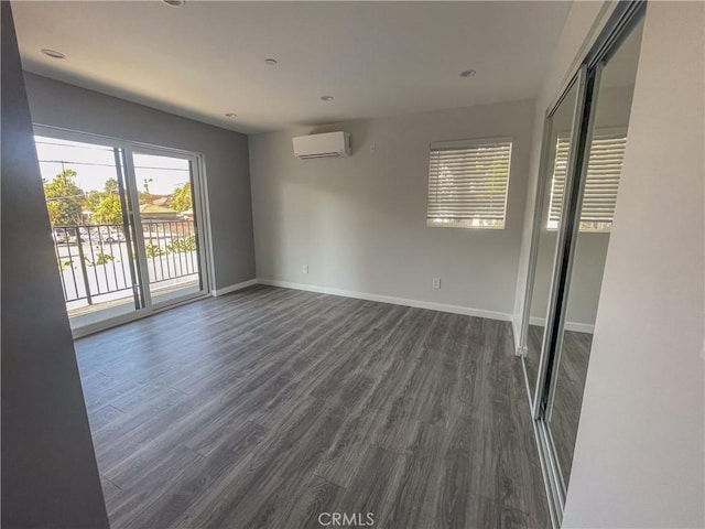 empty room featuring an AC wall unit, dark wood-style flooring, recessed lighting, and baseboards