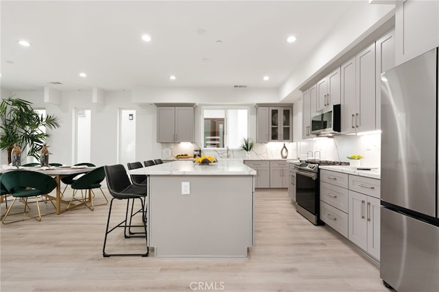 kitchen with a kitchen bar, gray cabinets, stainless steel appliances, and a kitchen island