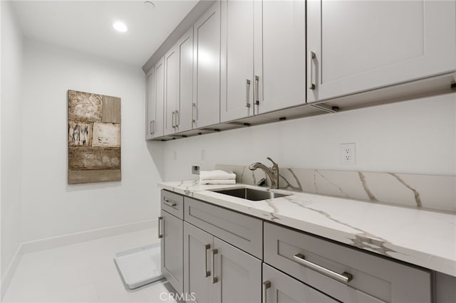 kitchen with gray cabinets, sink, and light stone counters