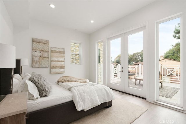 bedroom featuring multiple windows, access to outside, and light wood-type flooring