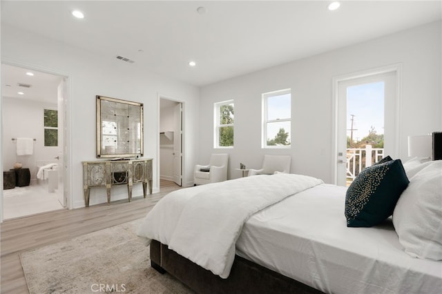 bedroom featuring ensuite bath, multiple windows, and light hardwood / wood-style flooring