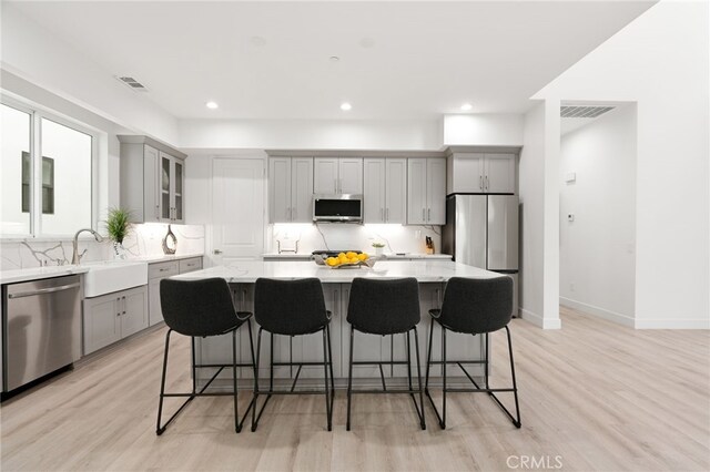 kitchen featuring sink, a breakfast bar area, gray cabinets, a kitchen island, and stainless steel appliances