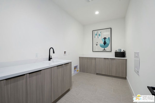 laundry area with sink, hookup for a washing machine, and cabinets