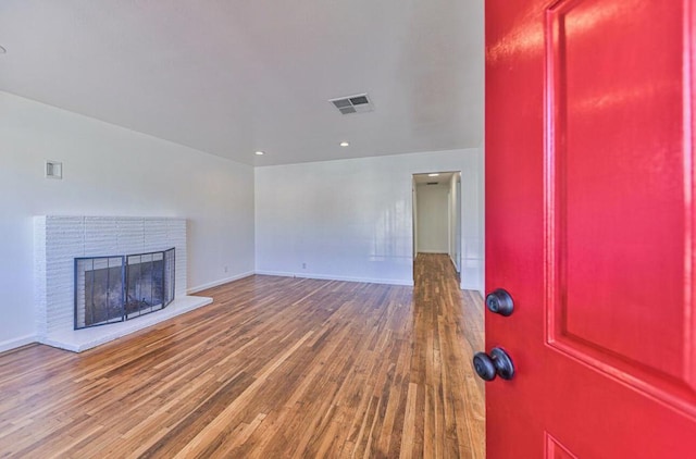 unfurnished living room with hardwood / wood-style flooring and a brick fireplace