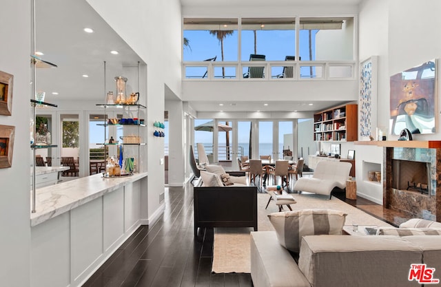 living room with a water view, a towering ceiling, and a premium fireplace