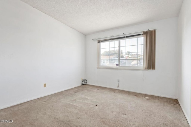 spare room featuring a textured ceiling and light carpet