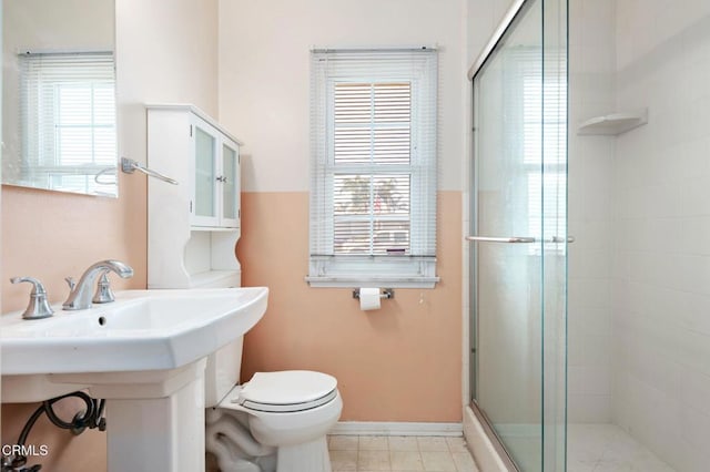 bathroom with toilet, sink, and a shower with door