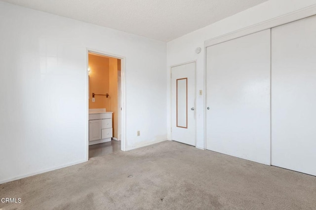 unfurnished bedroom with a closet, light colored carpet, and ensuite bath