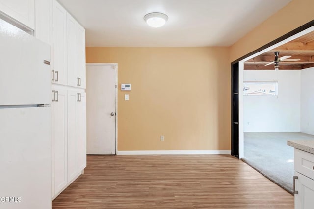 unfurnished room with ceiling fan, light wood-type flooring, and beamed ceiling