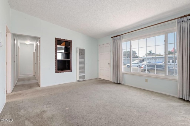 spare room featuring light carpet, vaulted ceiling, and a textured ceiling