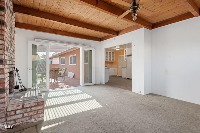 interior space featuring wood ceiling, ceiling fan, carpet floors, a fireplace, and beamed ceiling