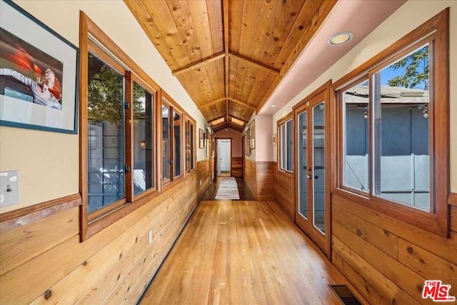 hall featuring a healthy amount of sunlight, french doors, wooden walls, and wooden ceiling