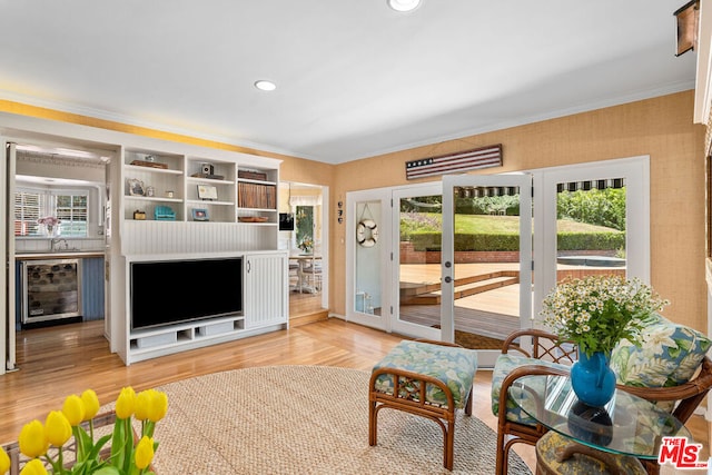 living room with hardwood / wood-style flooring, crown molding, a wealth of natural light, and beverage cooler