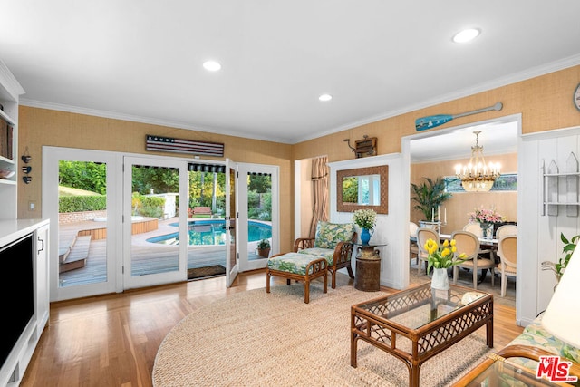 living room with ornamental molding, hardwood / wood-style floors, and a notable chandelier