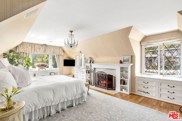 bedroom with lofted ceiling, a chandelier, and light hardwood / wood-style floors