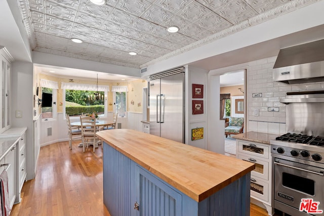 kitchen with a center island, premium appliances, blue cabinets, wood counters, and light wood-type flooring