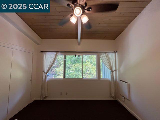 empty room featuring vaulted ceiling, ceiling fan, and wooden ceiling