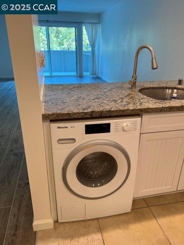 laundry area featuring sink, washer / clothes dryer, cabinets, and light tile patterned flooring