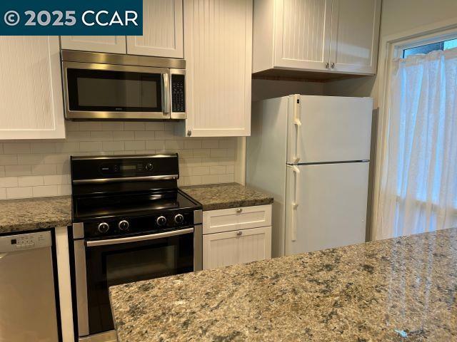 kitchen with electric range oven, dishwashing machine, white cabinets, white refrigerator, and tasteful backsplash