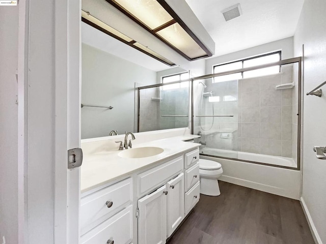 full bathroom with wood-type flooring, toilet, vanity, and combined bath / shower with glass door