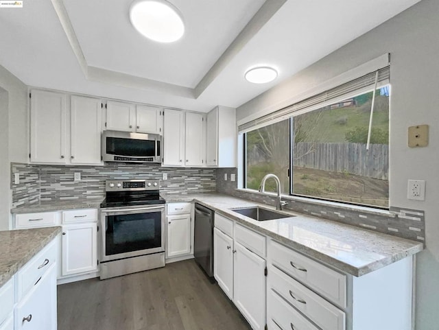 kitchen with sink, stainless steel appliances, white cabinetry, and light stone countertops