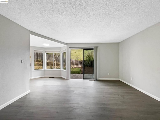 unfurnished room with dark hardwood / wood-style floors and a textured ceiling