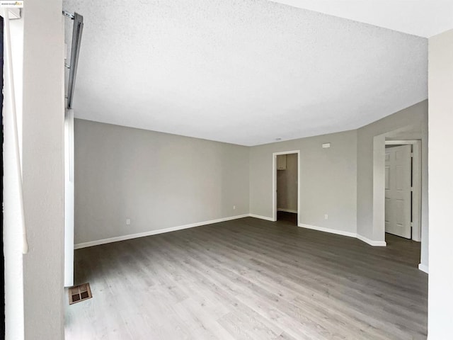 unfurnished room featuring hardwood / wood-style flooring and a textured ceiling