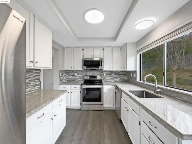 kitchen featuring appliances with stainless steel finishes, sink, white cabinets, light stone counters, and decorative backsplash