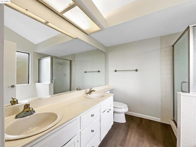 bathroom featuring hardwood / wood-style flooring, toilet, a shower with shower door, and vanity