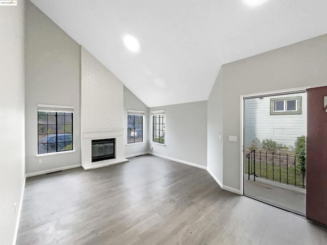 unfurnished living room featuring a fireplace, hardwood / wood-style floors, and high vaulted ceiling