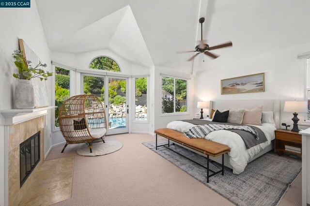 bedroom with a tile fireplace, ceiling fan, multiple windows, light carpet, and access to outside