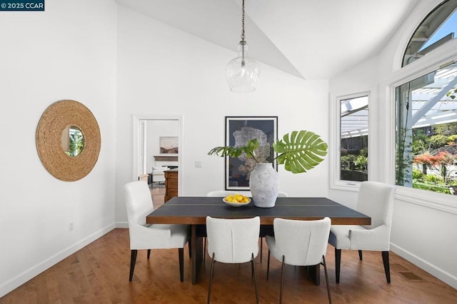 dining space with lofted ceiling, dark wood-type flooring, and a wealth of natural light