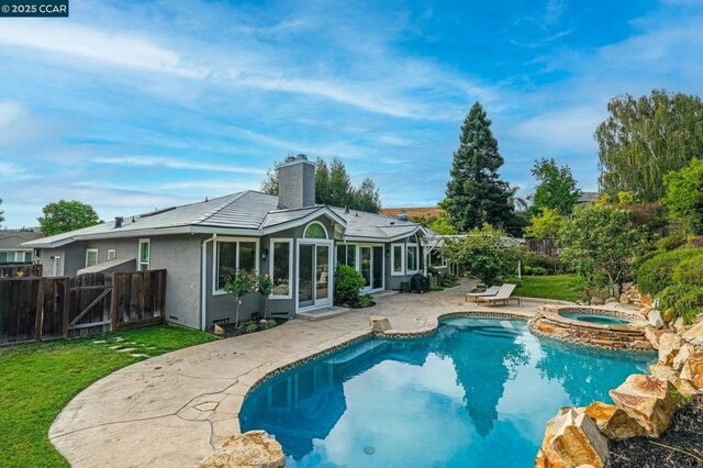 back of house featuring a patio, a sunroom, a yard, and a pool with hot tub