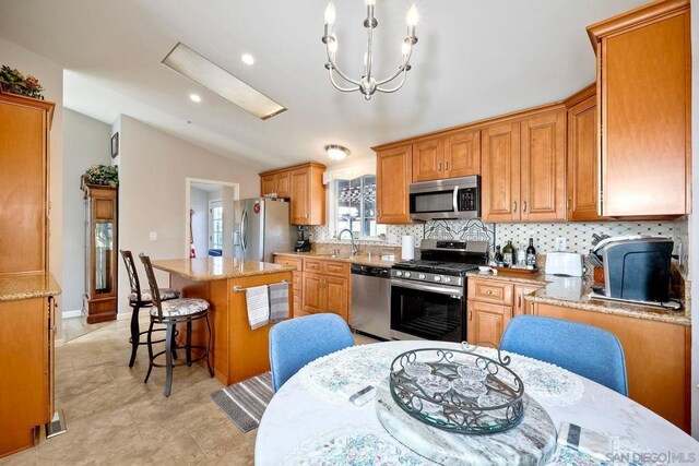 kitchen featuring sink, a breakfast bar area, a center island, vaulted ceiling, and stainless steel appliances