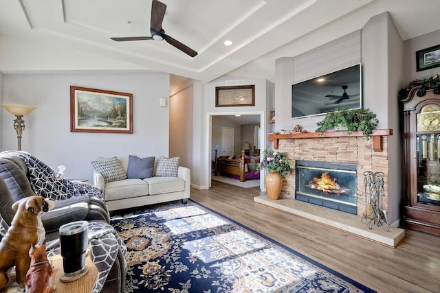 living room featuring ceiling fan, a fireplace, a raised ceiling, and hardwood / wood-style floors