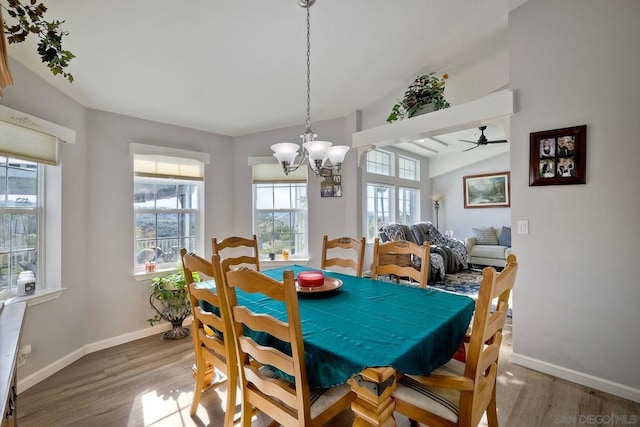 dining room featuring wood-type flooring, vaulted ceiling, and a notable chandelier