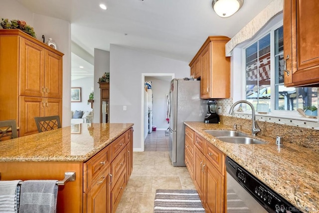 kitchen with lofted ceiling, sink, light stone counters, a center island, and appliances with stainless steel finishes