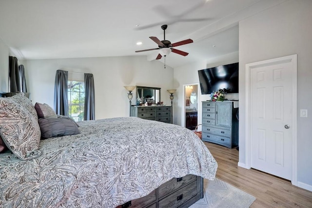 bedroom featuring ceiling fan, light hardwood / wood-style floors, ensuite bath, and vaulted ceiling with beams