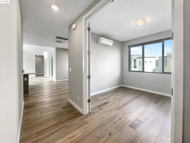 spare room with wood-type flooring and an AC wall unit