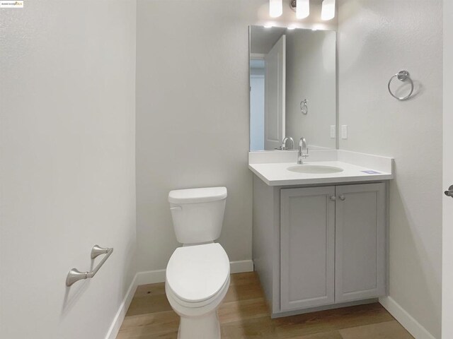 bathroom with wood-type flooring, toilet, and vanity