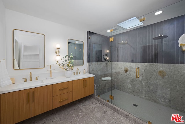 bathroom with vanity, a skylight, and a shower with door