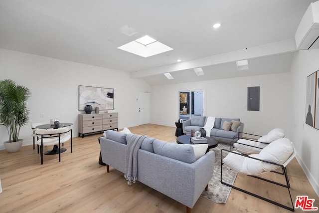 living room with a wall unit AC, electric panel, light hardwood / wood-style floors, and vaulted ceiling with skylight