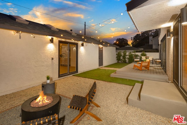 yard at dusk with an outdoor fire pit, a patio area, and a wooden deck