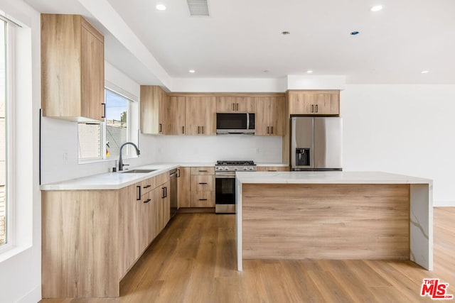 kitchen with a center island, appliances with stainless steel finishes, sink, and light hardwood / wood-style flooring